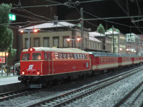 Rote ÖBB-Diesellok mit Personenzug am Bahnsteig